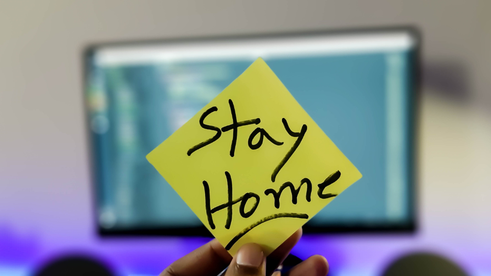 A person holding up a yellow sticky note with the handwritten message 